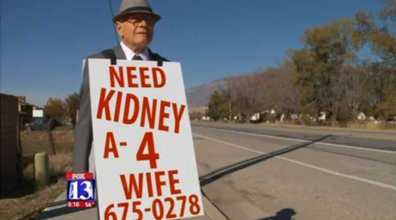An elderly man walking with advertisement Board: «Looking for kidney for wife»
