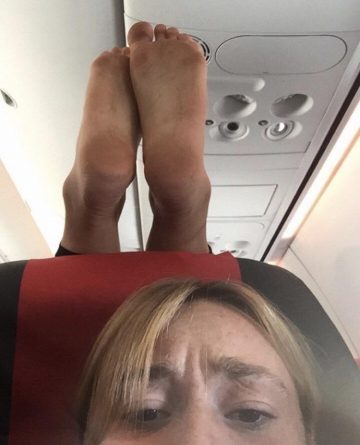 Passenger aircraft marked dirty bare feet «on the head» sitting in front of a woman